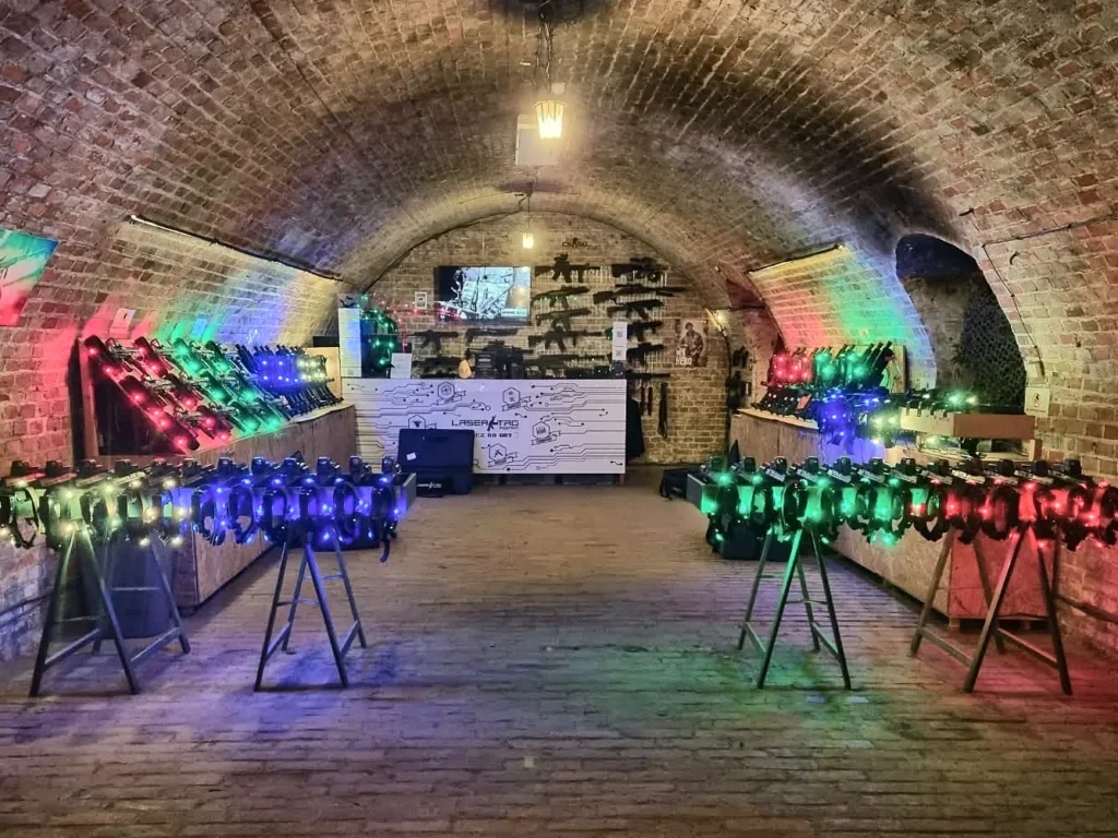 Sala szkoleniowa areny laser tag w Forcie Va – stanowiska z kamizelkami i karabinami podświetlonymi kolorowymi LED-ami
